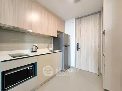Modern kitchen with sleek cabinetry, stainless steel fridge, and built-in microwave in a stylish apartment.