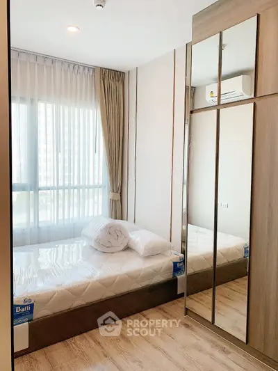 Modern bedroom with mirrored wardrobe and large window in a stylish apartment.