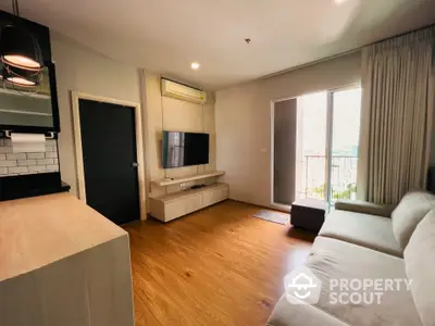 Modern living room with wooden flooring, cozy sofa, and balcony access.