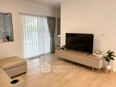 Modern living room with sleek TV stand, large window, and cozy seating area.