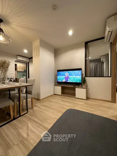 Modern living room with stylish decor and open dining area, featuring sleek wooden flooring and ambient lighting.