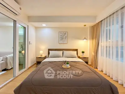 Cozy bedroom with modern decor and natural light, featuring a comfortable bed and stylish lighting.