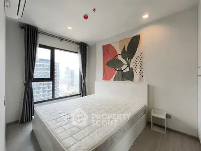 Modern bedroom with large window offering city view, stylish decor, and natural light.
