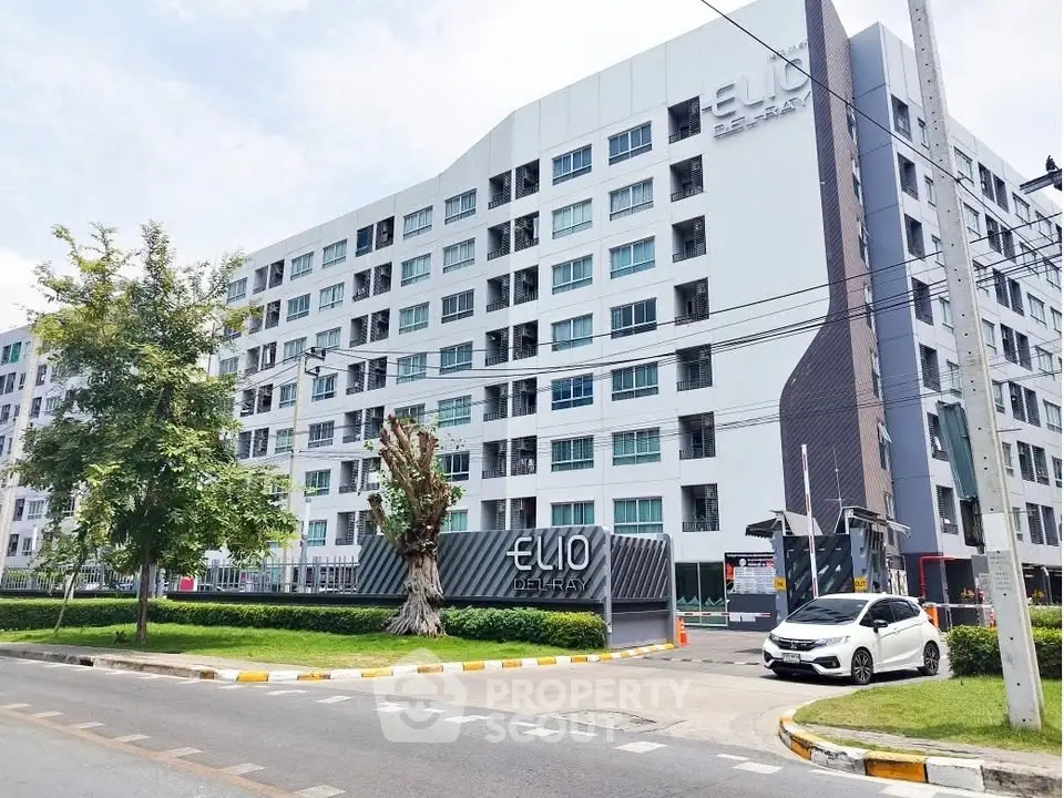 Modern residential building exterior with lush landscaping and street view.