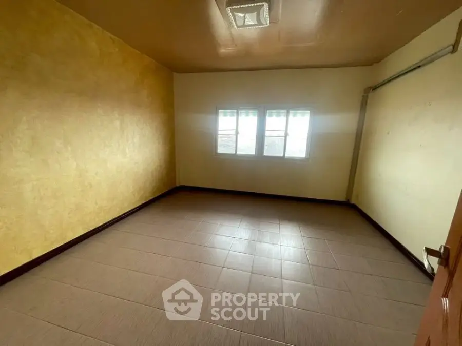 Spacious empty room with tiled floor and natural light from windows.