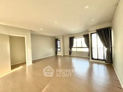 Spacious empty living room with large windows and balcony access, perfect for customization.