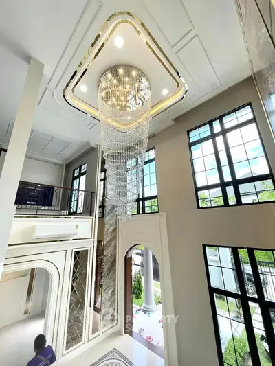 Luxurious high-ceiling living room with grand chandelier and large windows