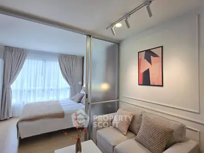 Modern apartment with cozy living room and elegant bedroom separated by glass partition.