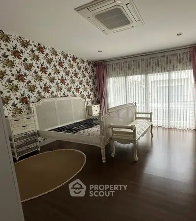 Charming bedroom with floral wallpaper and elegant furniture, featuring large windows for natural light.