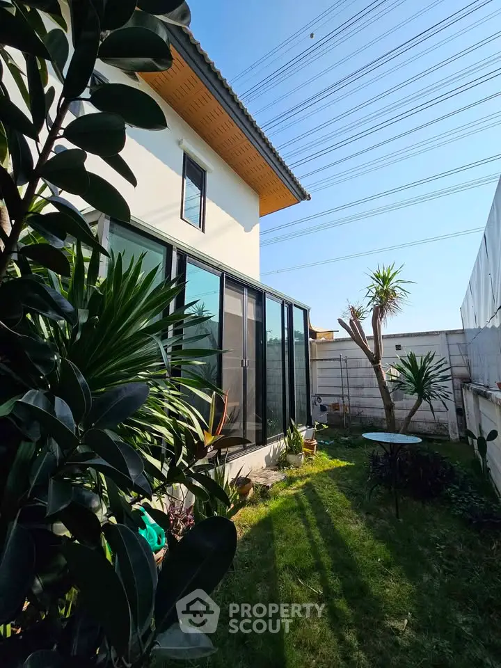 Charming garden view of modern home with lush greenery and large glass doors.
