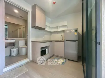 Modern compact kitchen with adjacent bathroom, featuring sleek cabinetry and stainless steel appliances.