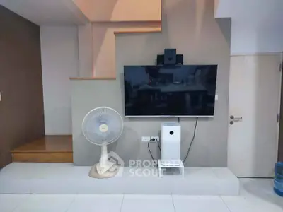 Modern living room with wall-mounted TV and sleek fan under staircase