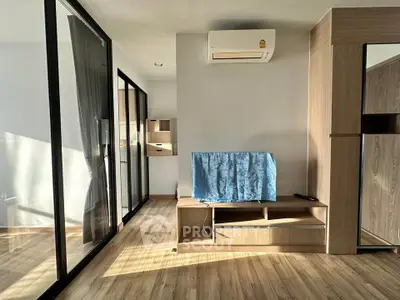 Modern living room with wooden flooring and air conditioning, featuring a sleek design and ample natural light.