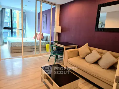 Modern apartment interior with cozy living room and stylish bedroom separated by glass wall.
