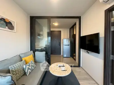 Modern living room with stylish decor and open kitchen view, featuring cozy seating and wall-mounted TV.