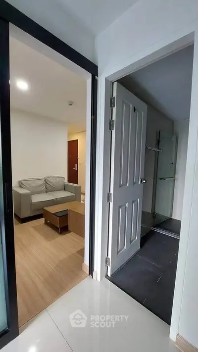 Modern apartment interior with cozy living room and bathroom entrance, featuring sleek design and neutral tones.
