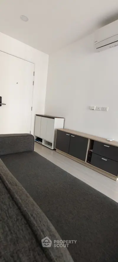 Modern living room with sleek furniture and air conditioning unit, showcasing minimalist design.