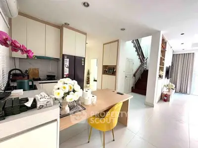 Modern kitchen with open layout and stylish dining area featuring bright yellow chair and elegant decor.