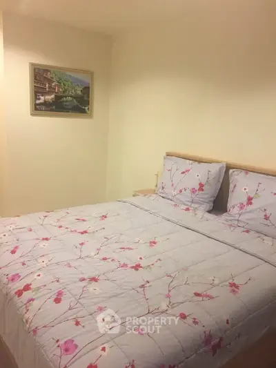 Cozy bedroom with floral bedding and wall art, perfect for relaxation.