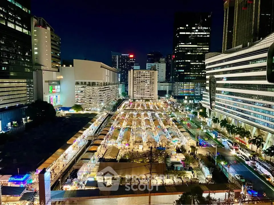 Stunning night view of a bustling cityscape with illuminated buildings and vibrant market below.