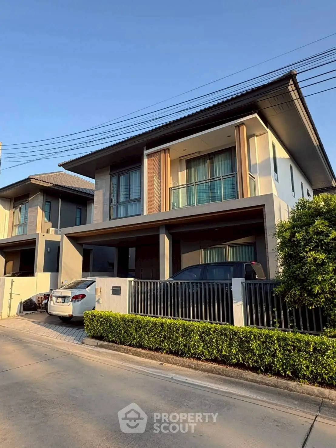 Modern two-story house with driveway and lush greenery in a serene neighborhood.