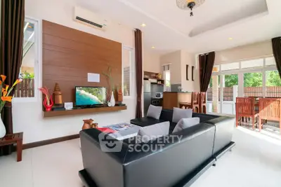 Spacious modern living room with sleek black sofas and abundant natural light.