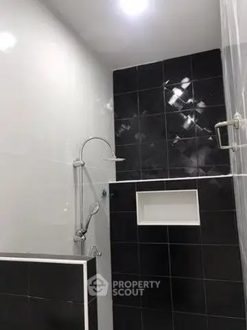 Modern bathroom with sleek black and white tiles and built-in shower nook.