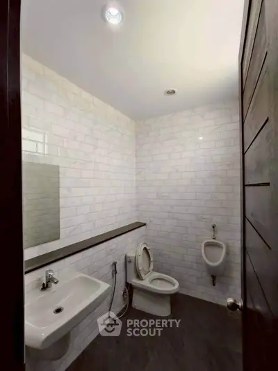 Modern bathroom with white tile walls and sleek fixtures.