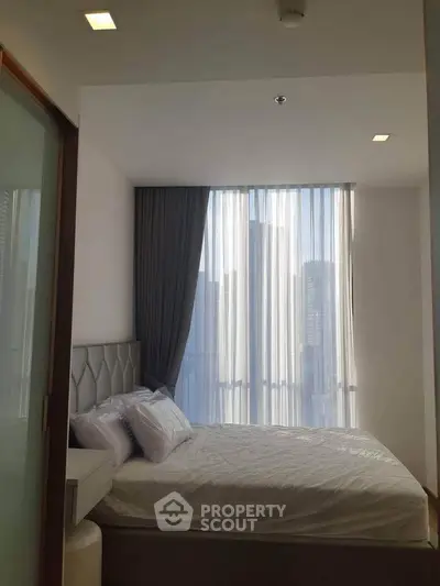Modern bedroom with large window and city view, featuring elegant decor and natural light.
