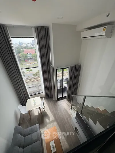 Modern loft apartment with high ceilings and city view from balcony.