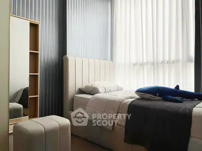 Cozy bedroom with modern decor and natural light, featuring a plush bed and stylish mirror.