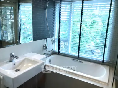 Modern bathroom with large window and bathtub, featuring sleek design and natural light.