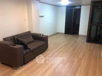 Spacious living room with wooden flooring and modern sofa in a cozy apartment.