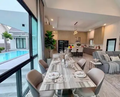 Luxurious open-plan living and dining area with pool view, modern kitchen, and elegant decor.