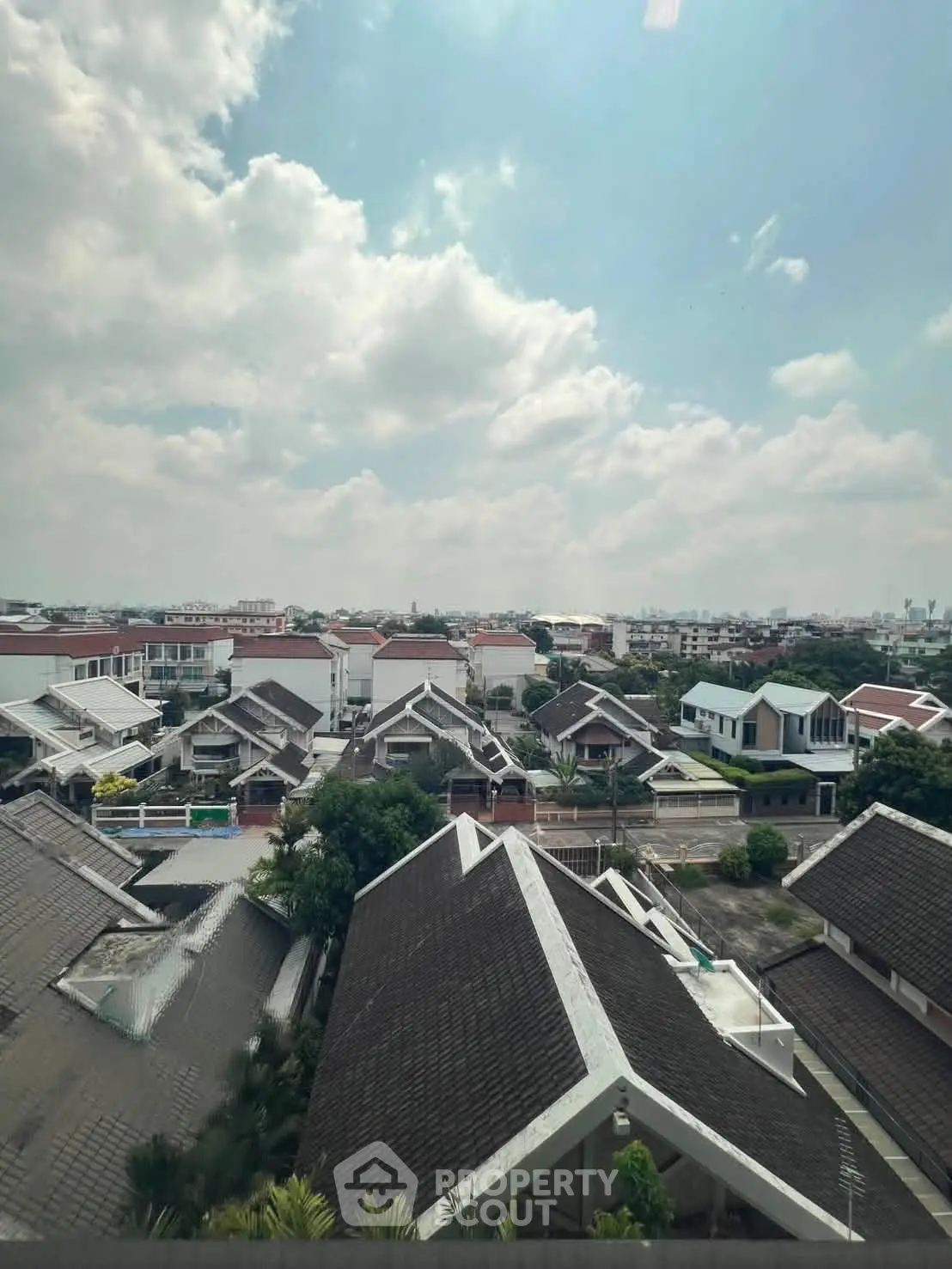 Stunning aerial view of suburban homes under a bright blue sky with fluffy clouds, showcasing a peaceful neighborhood.