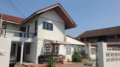 Charming two-story house with red-tiled roof and spacious front yard in sunny neighborhood.