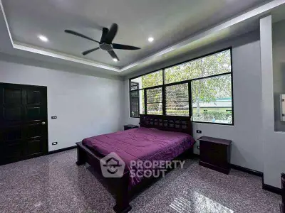 Spacious bedroom with modern ceiling fan and large window offering natural light.