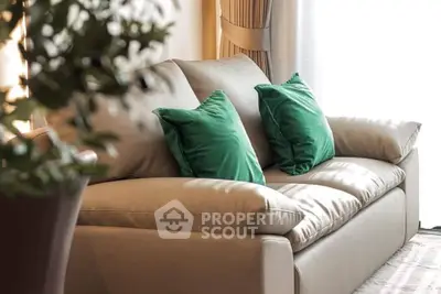 Elegant living room with plush beige sofa and vibrant green cushions, bathed in natural light.