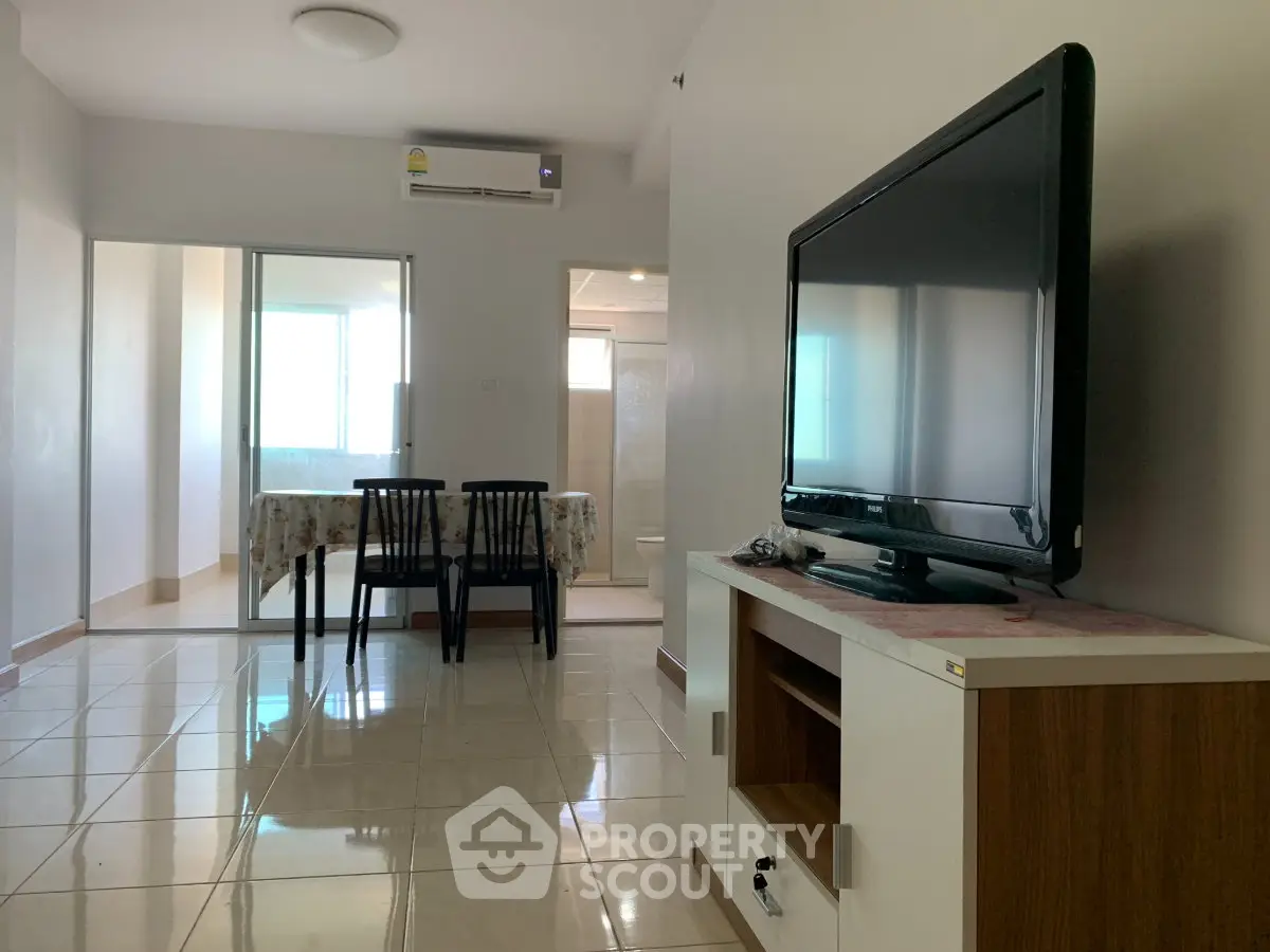 Modern living room with sleek TV setup and dining area in open layout apartment.