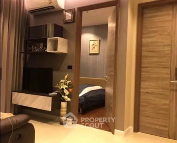 Modern living room with open view into cozy bedroom, featuring stylish decor and air conditioning.