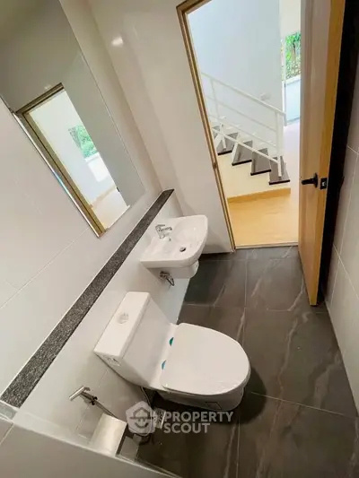 Modern bathroom with sleek fixtures and a view of a stylish staircase