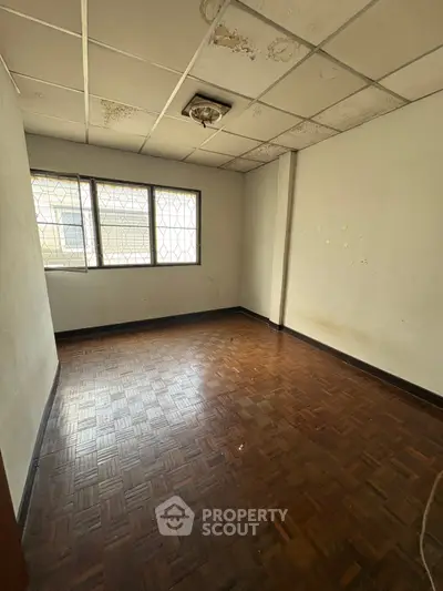 Spacious room with parquet flooring and large window, ideal for customization.