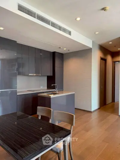 Modern kitchen with sleek cabinetry and dining area in open layout apartment.