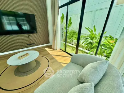 Modern living room with large windows and garden view, featuring a sleek TV and cozy sofa.