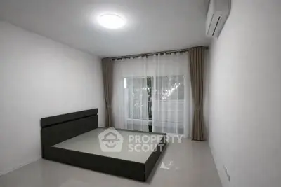 Minimalist bedroom with large window and modern bed frame, perfect for serene living.