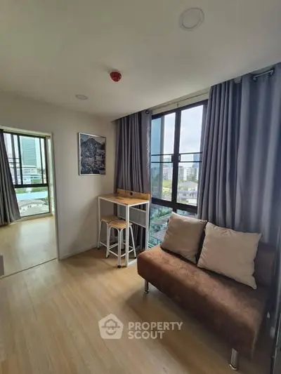 Modern living room with large window and city view, featuring cozy sofa and stylish decor.