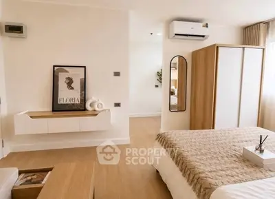 Modern bedroom with stylish decor, featuring a cozy bed, wooden wardrobe, and wall-mounted air conditioner.