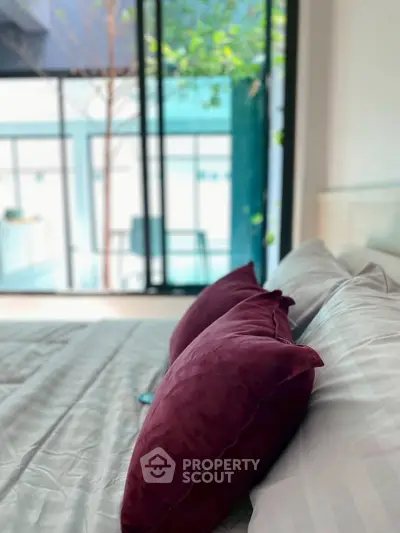 Luxurious bedroom with plush pillows and large windows offering serene outdoor views.