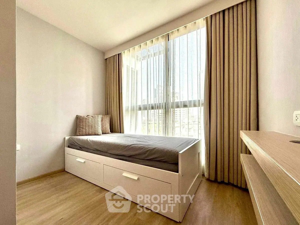 Bright bedroom with large window and modern furnishings in a stylish apartment.
