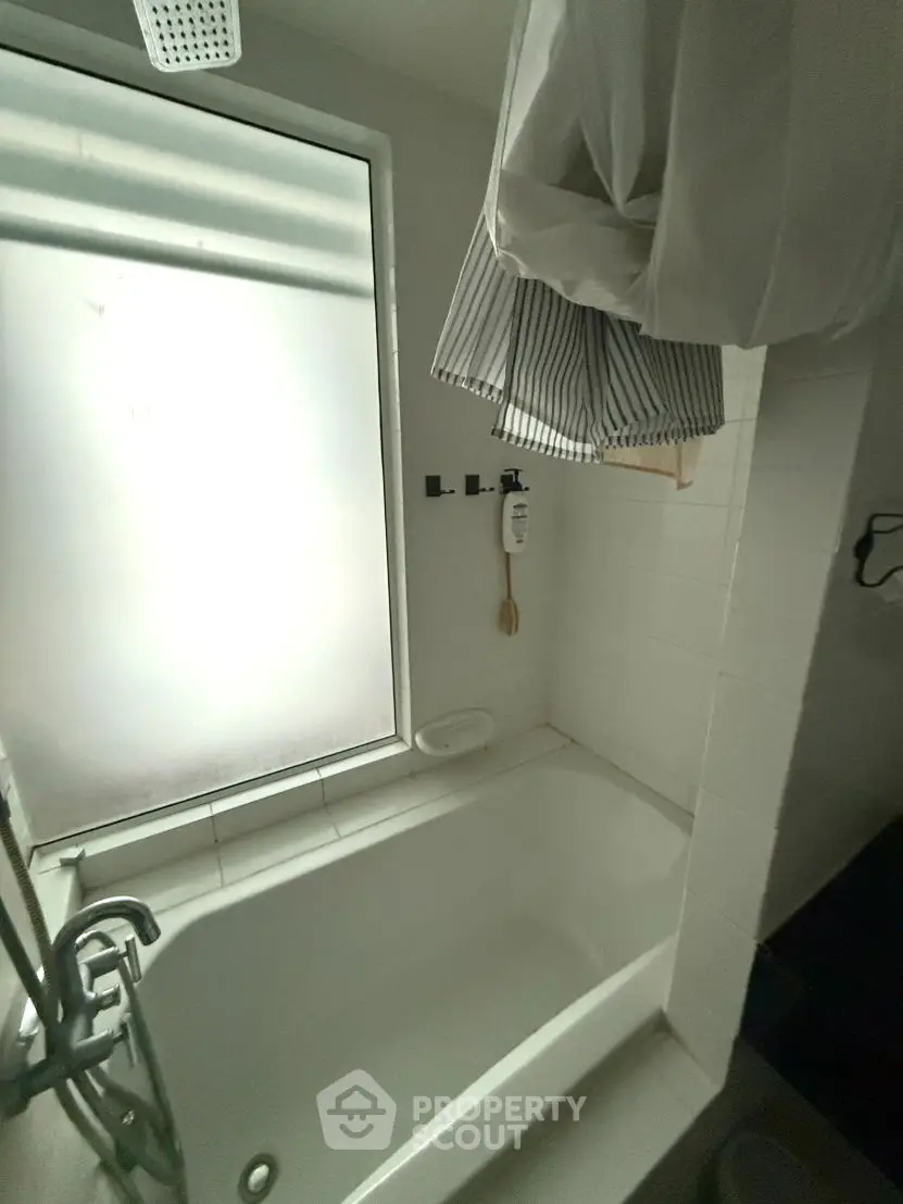 Compact bathroom with bathtub and frosted window for privacy.